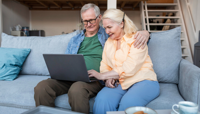 Starší manželský pár sleduje obrazovku na počítači.