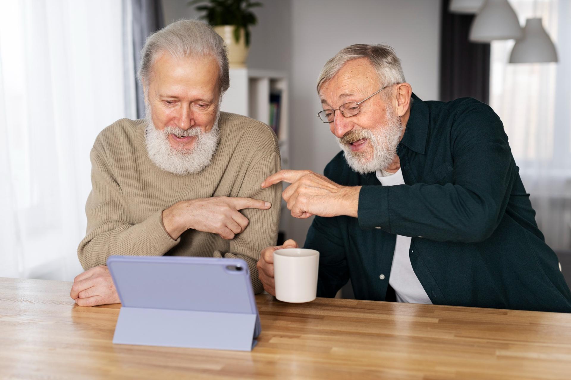 Dva senioři při rozhovoru nad počítačem