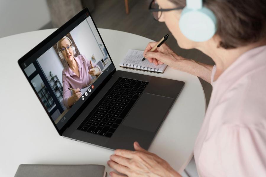 Paní se sluchátky sleduje on-line seminář.